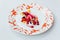 Modern French sweets:Â Strawberry mouse with merengue, rose, crumble & vanilla milk shake on white plate with red colour pattern